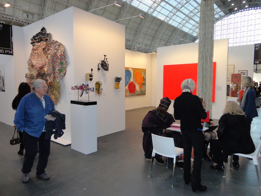 The celebrated Beninese artist Romuald Hazoumé (seated) on the stand of the October Gallery at ART14 London. Image Auction Central News.